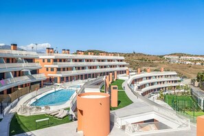 A modern hotel with multiple balconies, a swimming pool, and a view of the surrounding landscape. - Family-friendly 2-bedroom penthouse with a padel court (Mijas)