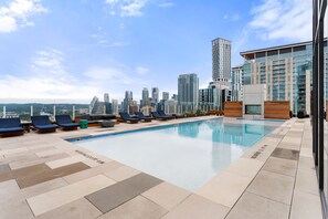 A rooftop pool with lounge chairs, a city skyline in the background, and modern buildings. - NEW Rainey Street Suite l Rooftop Pool l  ACL x F1 (Austin)