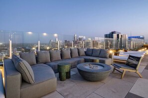 A rooftop lounge with a modern sofa set, a round coffee table, and a view of the city skyline at dusk. - NEW Rainey Street Suite l Rooftop Pool l  ACL x F1 (Austin)