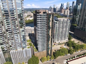 A high-rise residential building with multiple balconies, surrounded by other high-rise buildings and a body of water. - NEW Rainey Street Suite l Rooftop Pool l  ACL x F1 (Austin)