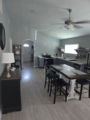 Une cuisine moderne dotée d’un îlot central, d’un coin repas avec des chaises et d’un ventilateur de plafond.