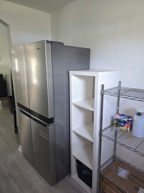 Ein Edelstahl-Kühlschrank, eine weiße Regaleinheit und ein Karton auf dem Boden.