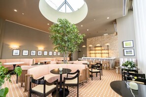 Un espacio interior moderno con disposiciones de asientos, un árbol central y un tragaluz circular.