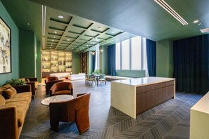 Un hall d’entrée moderne doté d’un comptoir de réception, d’un espace salon et d’une grande fenêtre laissant entrer la lumière naturelle.