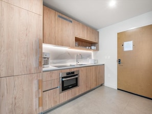 A modern kitchen with wooden cabinets, a built-in oven, and a stainless steel sink. - Sophisticated Miami 1BR The Crosby 2113 (Miami)