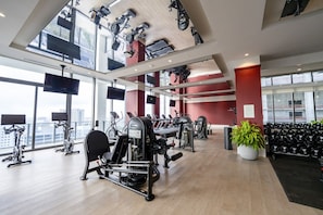 A gym with cardio machines, weightlifting equipment, and a large window offering a city view. - Sophisticated Miami 1BR The Crosby 2113 (Miami)