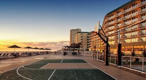 An outdoor basketball court with a net, surrounded by lounge chairs and umbrellas, adjacent to a multi-story building with balconies. - THANKSGIVING BEACH VACATION!!! ROYAL FLORIDIAN RESORT ORMOND BCH FL 7-DAY RENTAL (Ormond Beach)