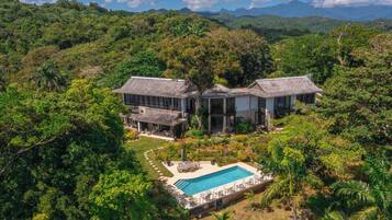 Une grande maison avec une piscine, entourée d’une végétation luxuriante.