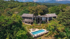 Ein geräumiges Haus mit Swimmingpool, umgeben von üppiger Bepflanzung.