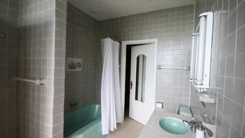 A bathroom with a bathtub, a sink, and a shower area.
