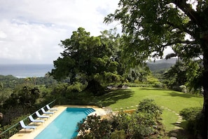 A pool with lounge chairs, a grassy area, and a view of the ocean. - Norse Hill Estate & Botanic Gardens (Port Antonio)