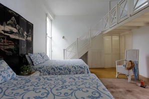 Ein Schlafzimmer mit zwei Betten, einem Sessel, einer Treppe und einem großen Gemälde an der Wand.