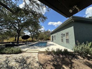 Una casa amb piscina, envoltada d'arbres i un cel serè.