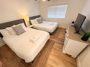 Ett hotellrum med två sängar, ett skrivbord, en TV och ett fönster med persienner.