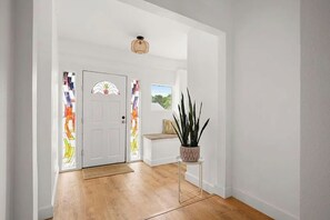 Ein Flur mit Holzboden, einer weißen Tür mit Glasmalerei und einem Blumentopf.