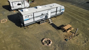 A recreational vehicle with a slide-out awning, a portable toilet, and a fire pit.