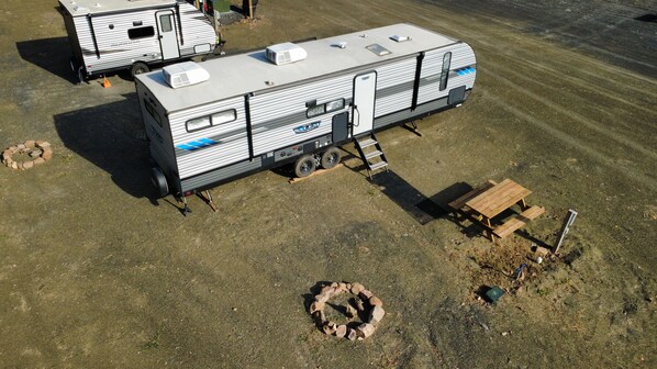 A recreational vehicle with a slide-out awning, a portable toilet, and a fire pit.