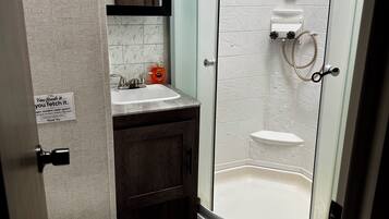 A bathroom with a toilet, sink, shower, and a sign on the wall.