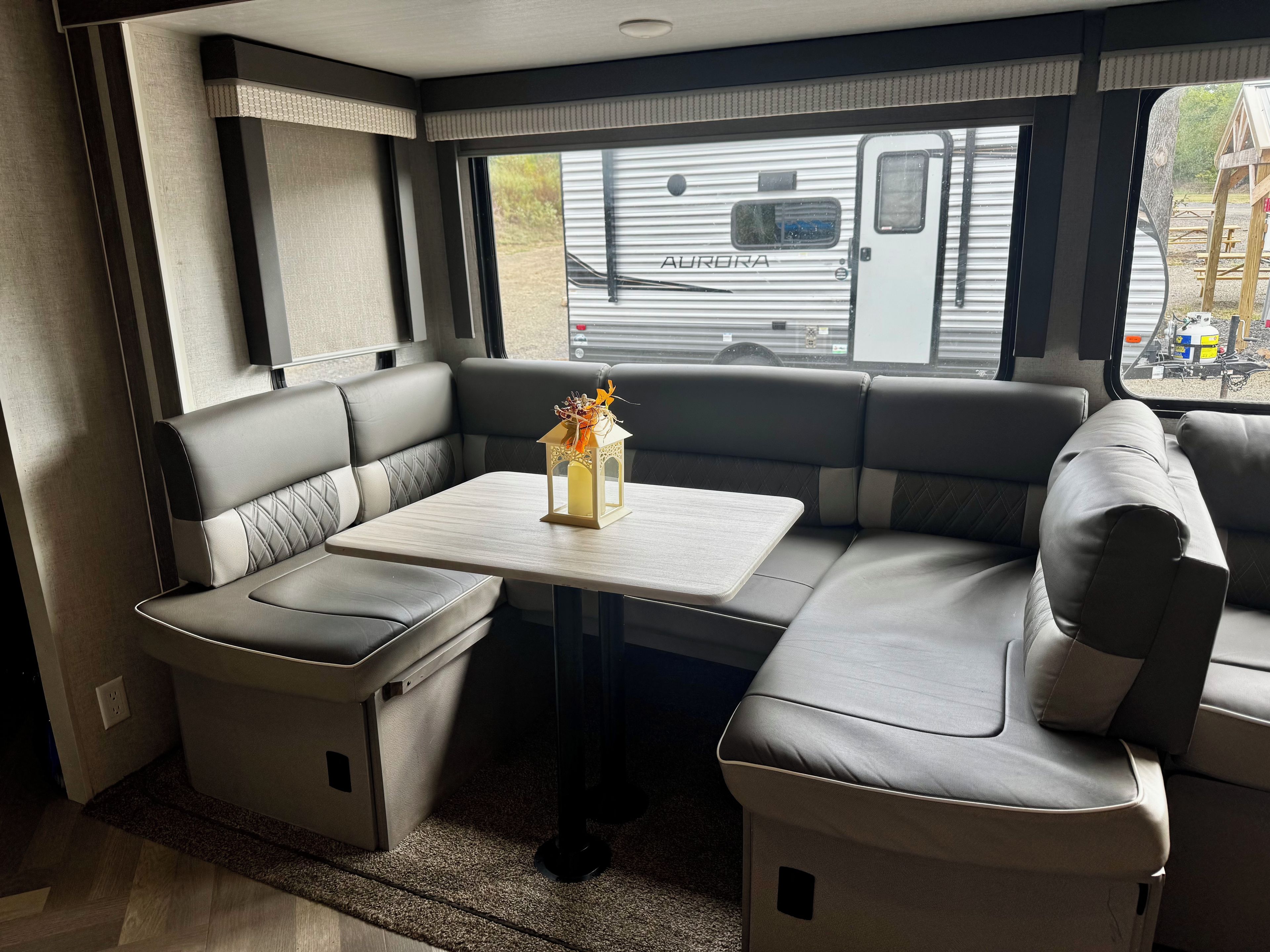 Interior compacto de una caravana con zona de comedor, una mesita y un banco.
