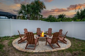 Ein kreisförmiger Außenbereich mit Adirondack-Stühlen um eine zentrale Feuerstelle.