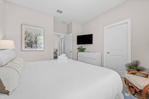 Ein Hotelzimmer mit einem großen Bett, einem an der Wand befestigten Fernseher und einer Tür zu einem anderen Raum.