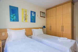 Ein Hotelzimmer mit zwei Betten, einem Kleiderschrank und drei Bildern an der Wand.
