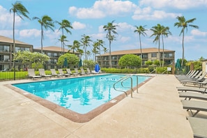 A swimming pool with lounge chairs and palm trees.