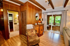 A room with wooden paneling, a patterned armchair, a wooden cabinet with a mirror, and a view of an outdoor deck. - Pet-Friendly Mountain Retreat, Fire Pit + 2 Decks (Banner Elk)