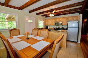 A kitchen with wooden cabinets, a refrigerator, and a dining area with a table and chairs. - Pet-Friendly Mountain Retreat, Fire Pit + 2 Decks (Banner Elk)