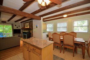 A kitchen with wooden cabinets, a granite countertop, and a dining area with a table and chairs. - Pet-Friendly Mountain Retreat, Fire Pit + 2 Decks (Banner Elk)