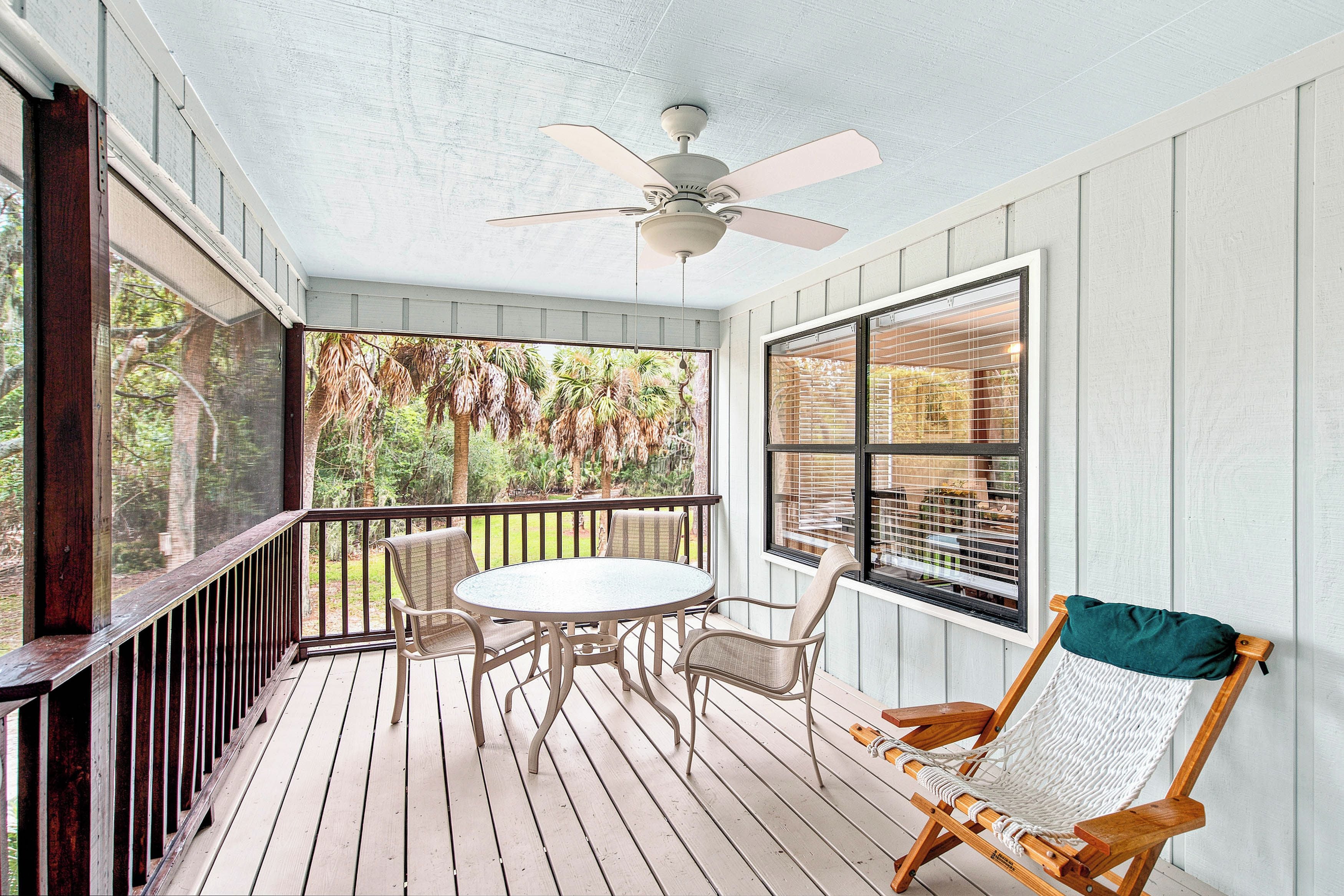 A covered porch with a table and chairs, a hammock, and a ceiling fan.