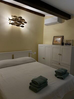 A bedroom with a bed, a wall-mounted light fixture, a framed picture, and a cabinet. - IL POGGIOLO. Nel cuore di Camogli, a soli 100 metri dal mare, (Camogli)