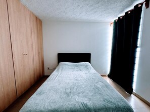 A bedroom with a bed, a wardrobe, and a window with curtains. - Anáhuac Relaxation Room (Oax.)