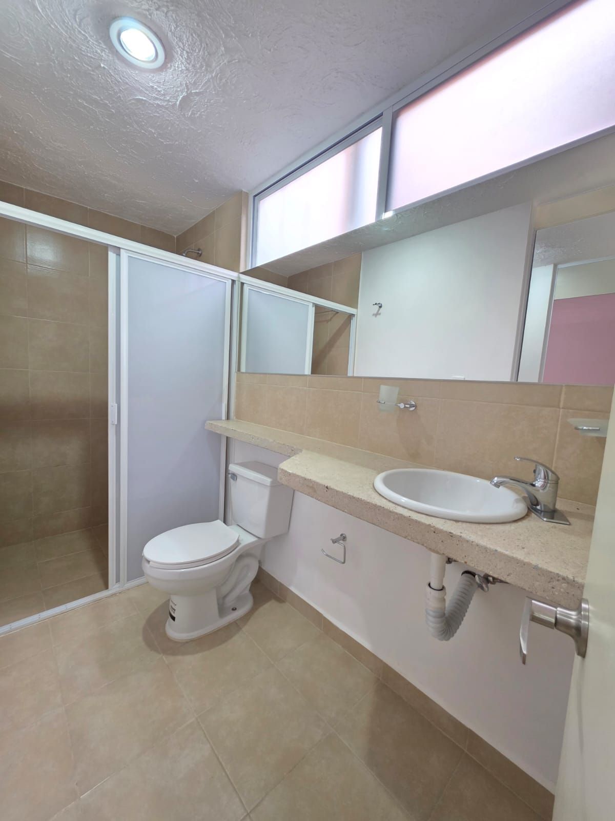 A bathroom with a toilet, a sink, and a shower enclosure.