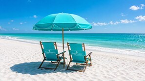 Two beach chairs with a turquoise umbrella on a sandy beach with clear blue water. - 5-Star Beachfront Condo, Edgewater Resort #1402 (Miramar Beach)