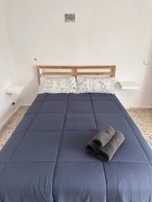 A single bed with a wooden headboard, a blue bedspread, and two pillows with a floral pattern. - Vacation Apartment 'A' with Wi-Fi and Air Conditioning (San José de los Llanos)