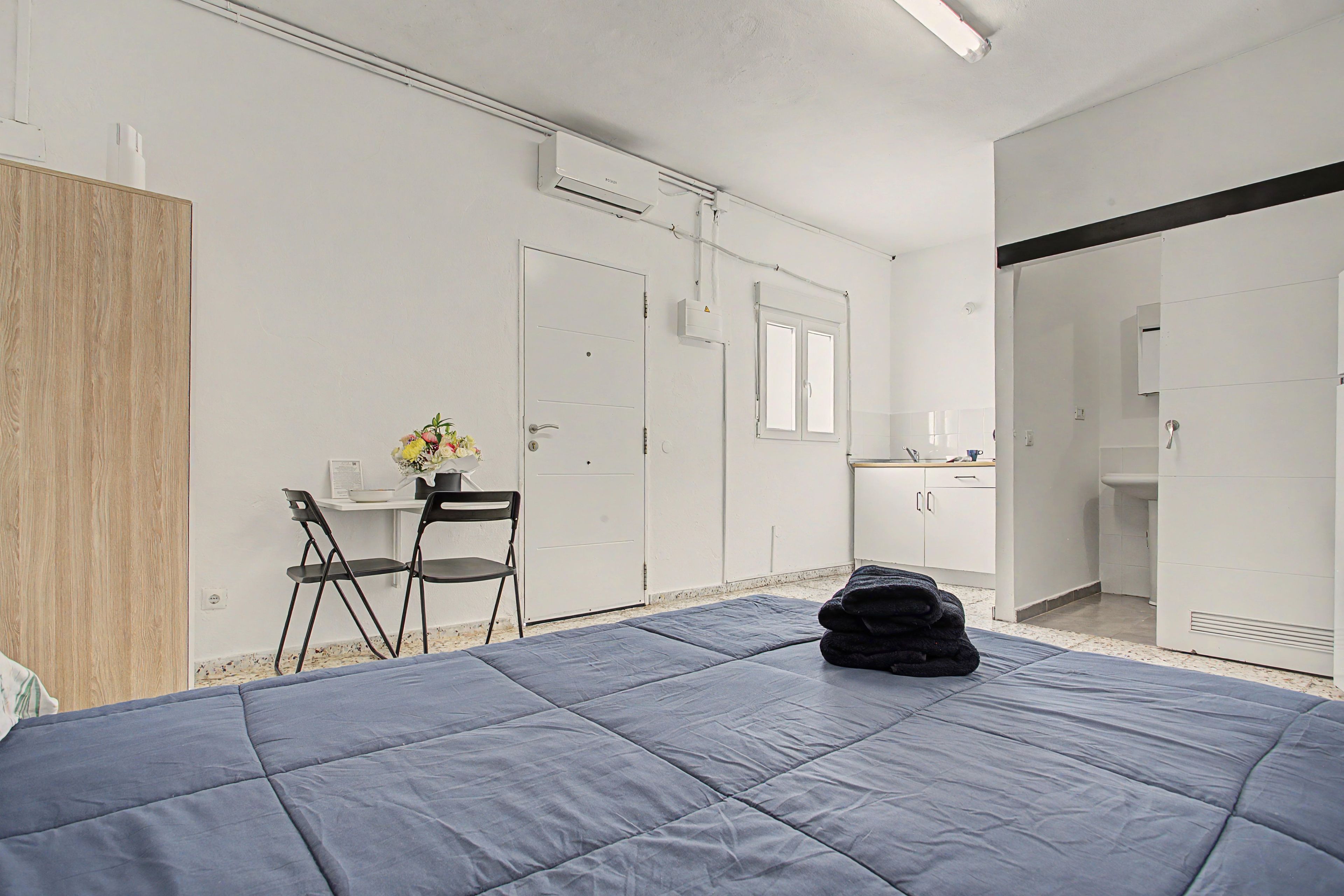 Un dormitorio con cama, escritorio, silla, espejo y armario.