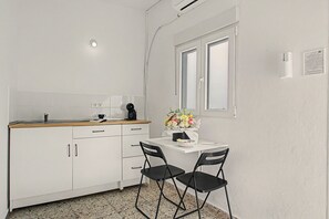A compact kitchen with white cabinets, a wooden countertop, a coffee maker, and a small table with chairs. - Vacation Apartment 'Paseo Por Las Nubes' with Wi-Fi and Air Conditioning (San José de los Llanos)