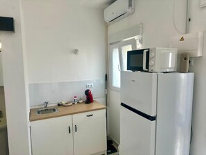 Eine kleine Küche mit einer Mikrowelle, einem Spülbecken und einem Kühlschrank.