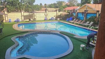 Una piscina de diseño curvo, rodeada de césped y una valla.