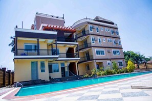 Un edificio residencial de varios pisos con una piscina delantera.