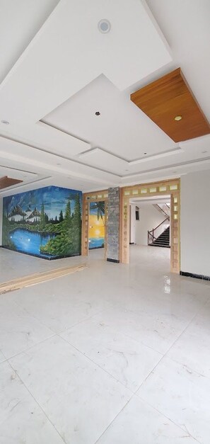 Un vestíbulo amplio con un mural grande, una escalera y un suelo pulido.