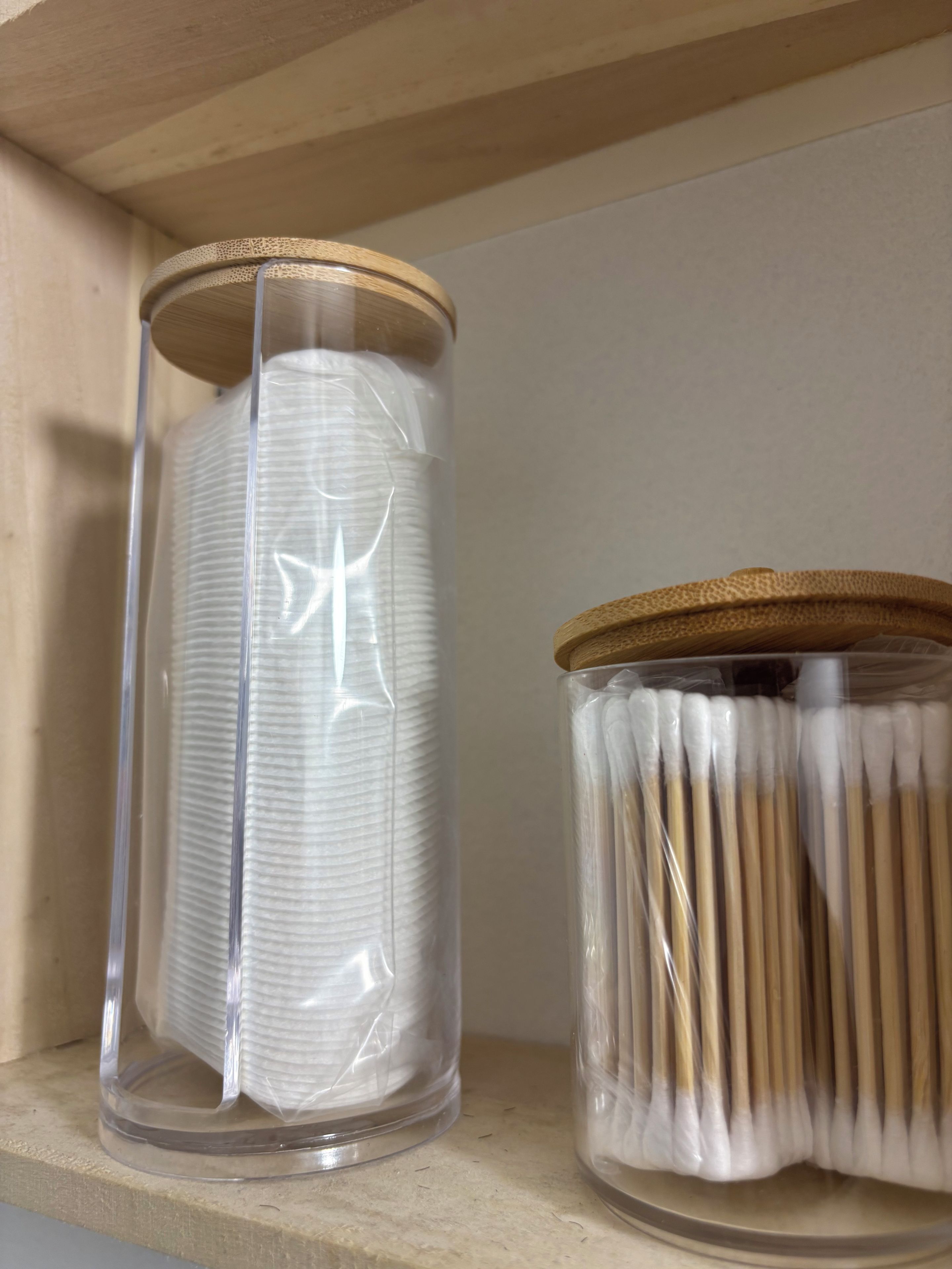 Two glass jars with wooden lids on a shelf.