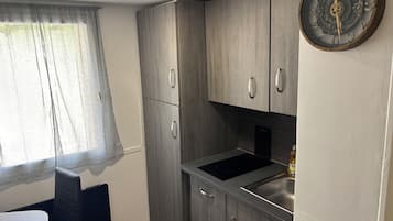 Una kitchenette compacta con estufa integrada, lavamanos y armarios.