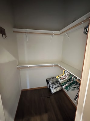 A compact closet with a wooden floor, white walls, and a metal rod for hanging clothes. - Charming 3-Bdrm home overlooking the Majestic Coos River with AC. (Coos Bay)