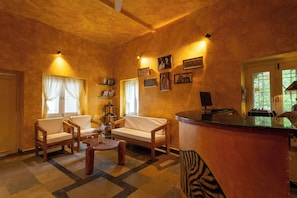 A cozy living room with a sofa, chairs, a coffee table, and a small bar area. - Heli Udaipur - A Century-Old Haveli (Udaipur)