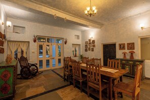 A dining area with wooden furniture, a chandelier, and a view through the window. - Heli Udaipur - A Century-Old Haveli (Udaipur)