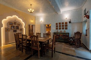 Un comedor con una mesa y sillas de madera, una araña y una pared decorativa con cuadros.