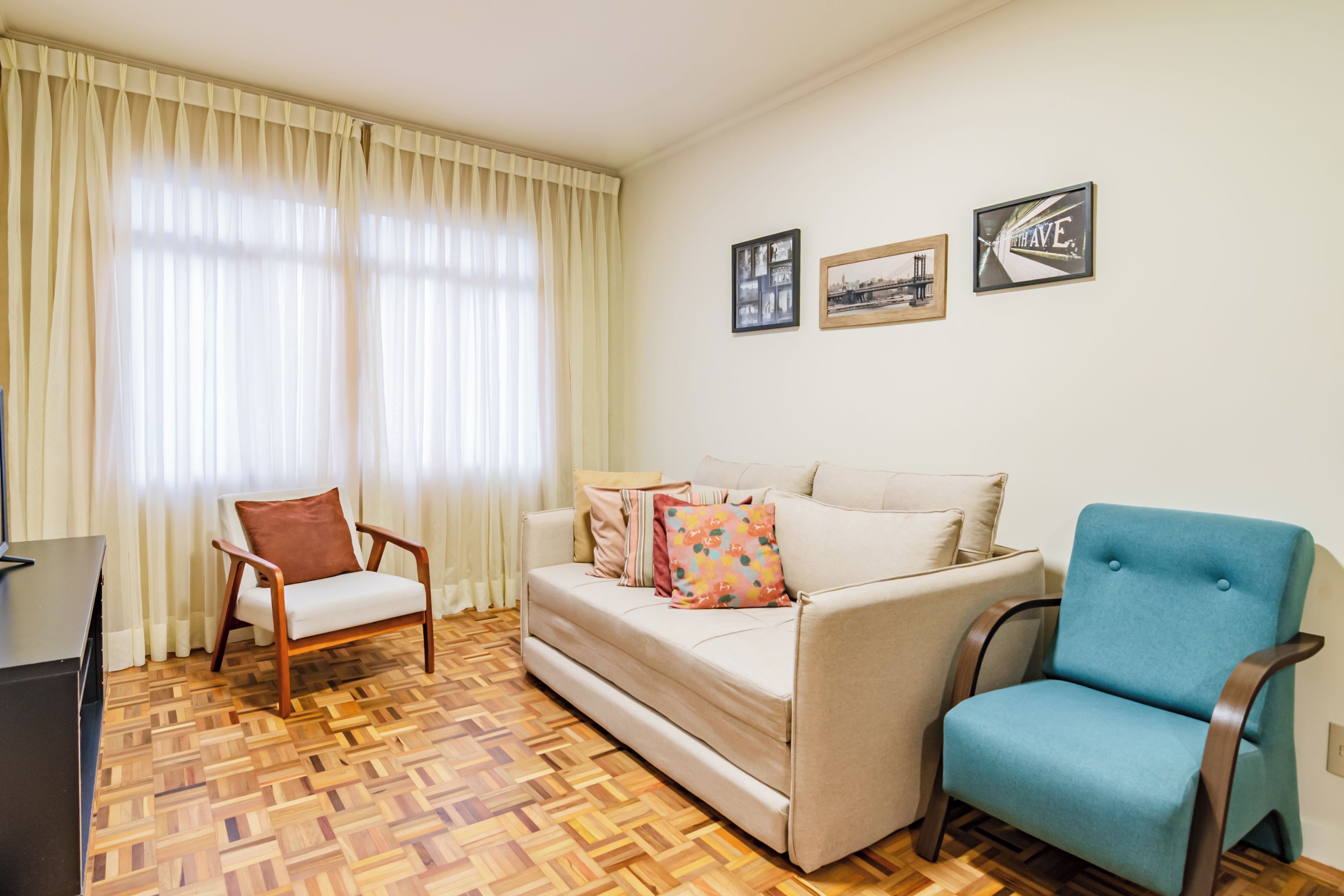 Una sala de estar con un sofá, un sillón azul, una silla de madera y un televisor.