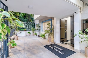 A hotel entrance with a black mat reading 'EDIFICIO ARNALDO ROSSI' and potted plants lining the path. - Rossi by Bhomy (São Paulo)